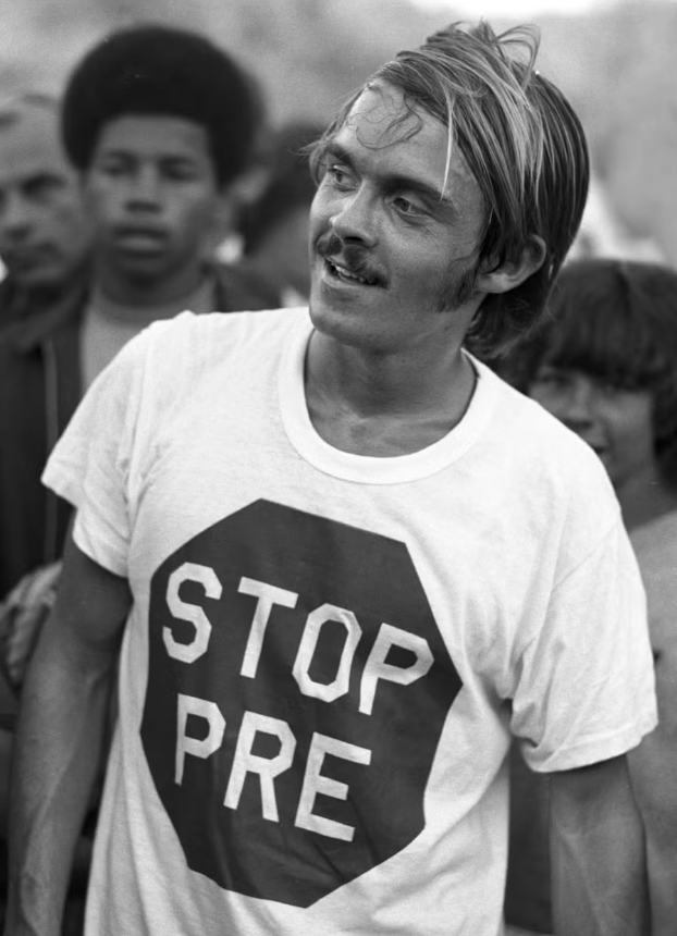 A man wearing a white t-shirt with the text "STOP PRE" printed on it.